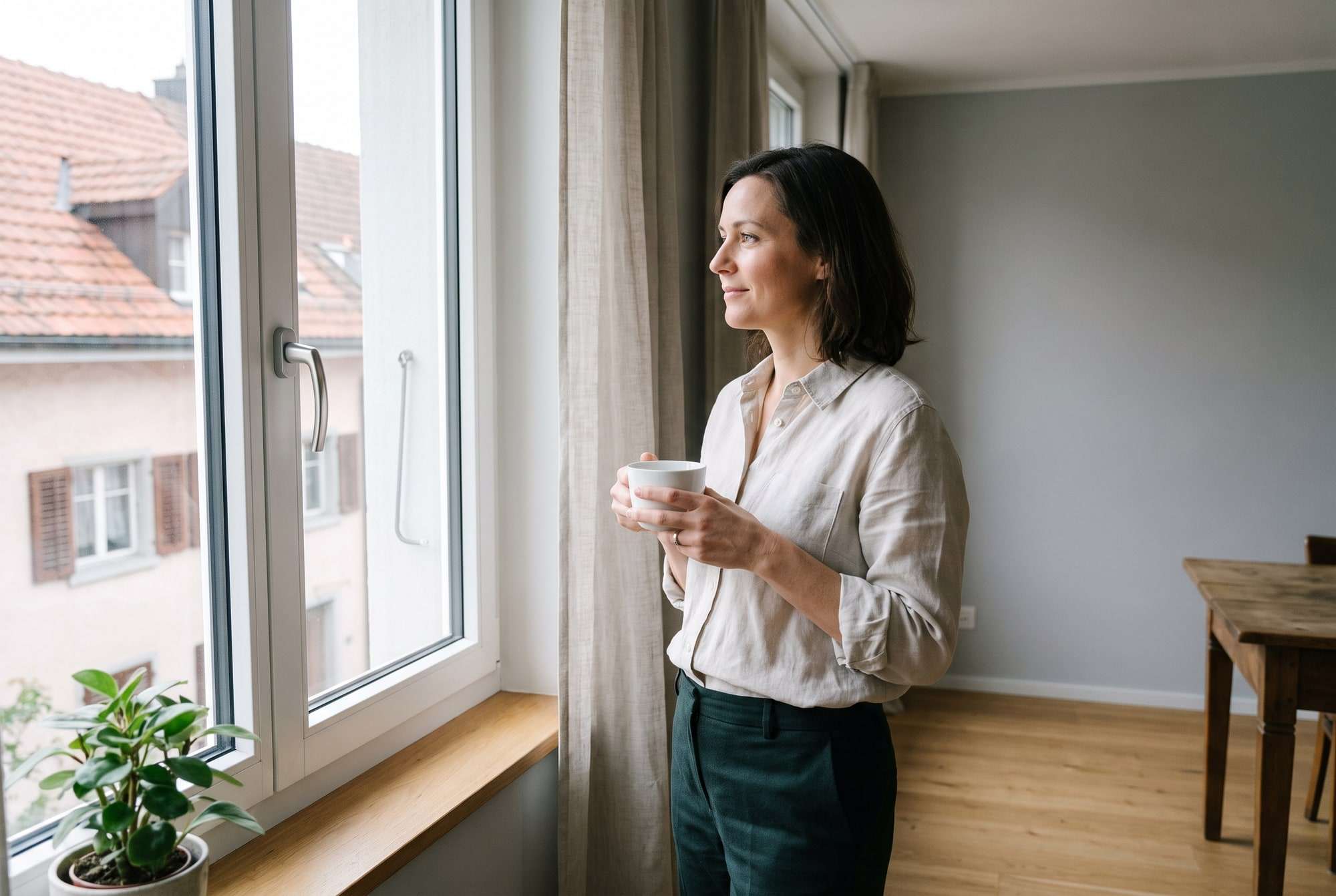 Femme avec une tasse près d’une fenêtre lumineuse