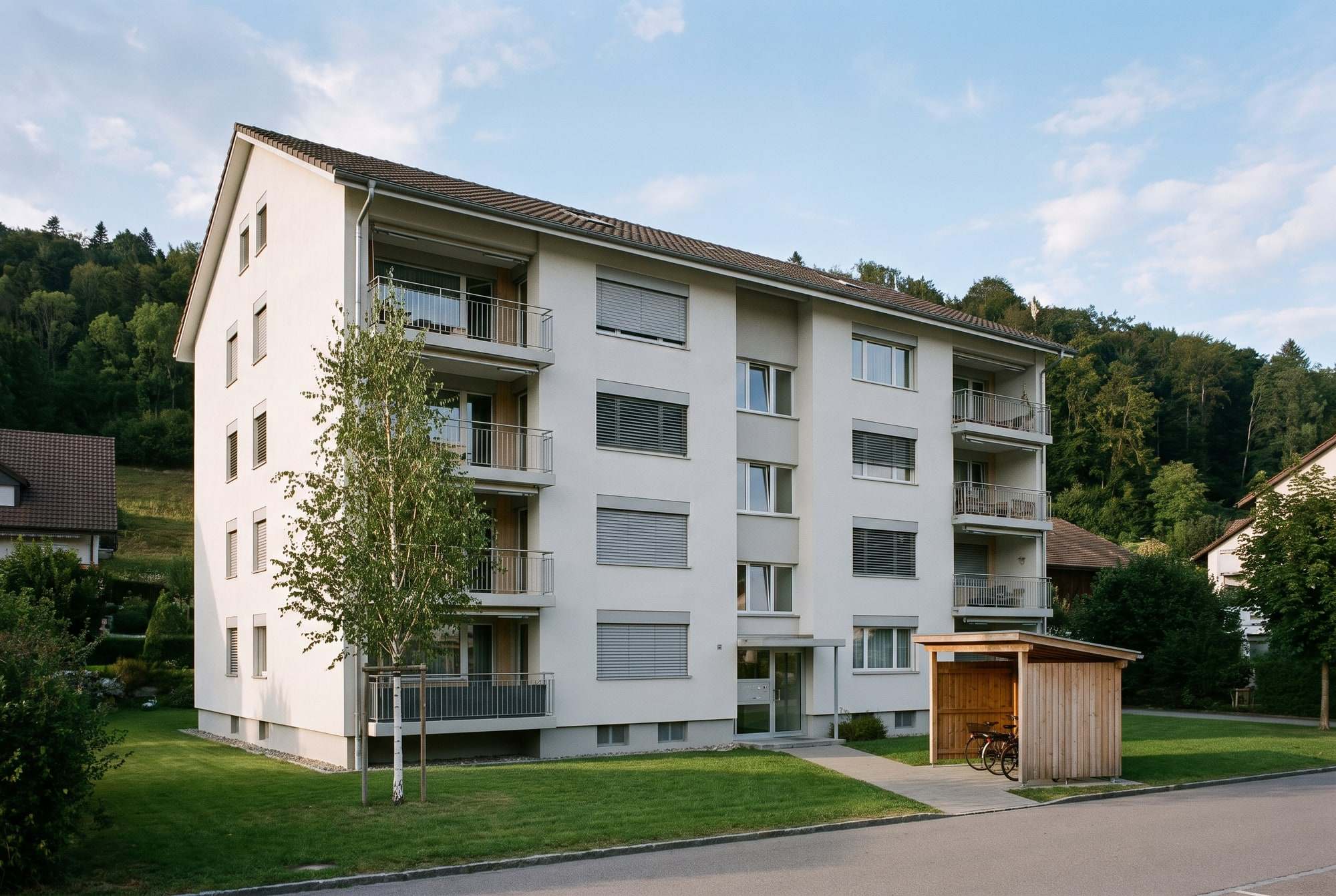 Immeuble locatif de quatre étages avec balcons, pelouse et abri à vélos