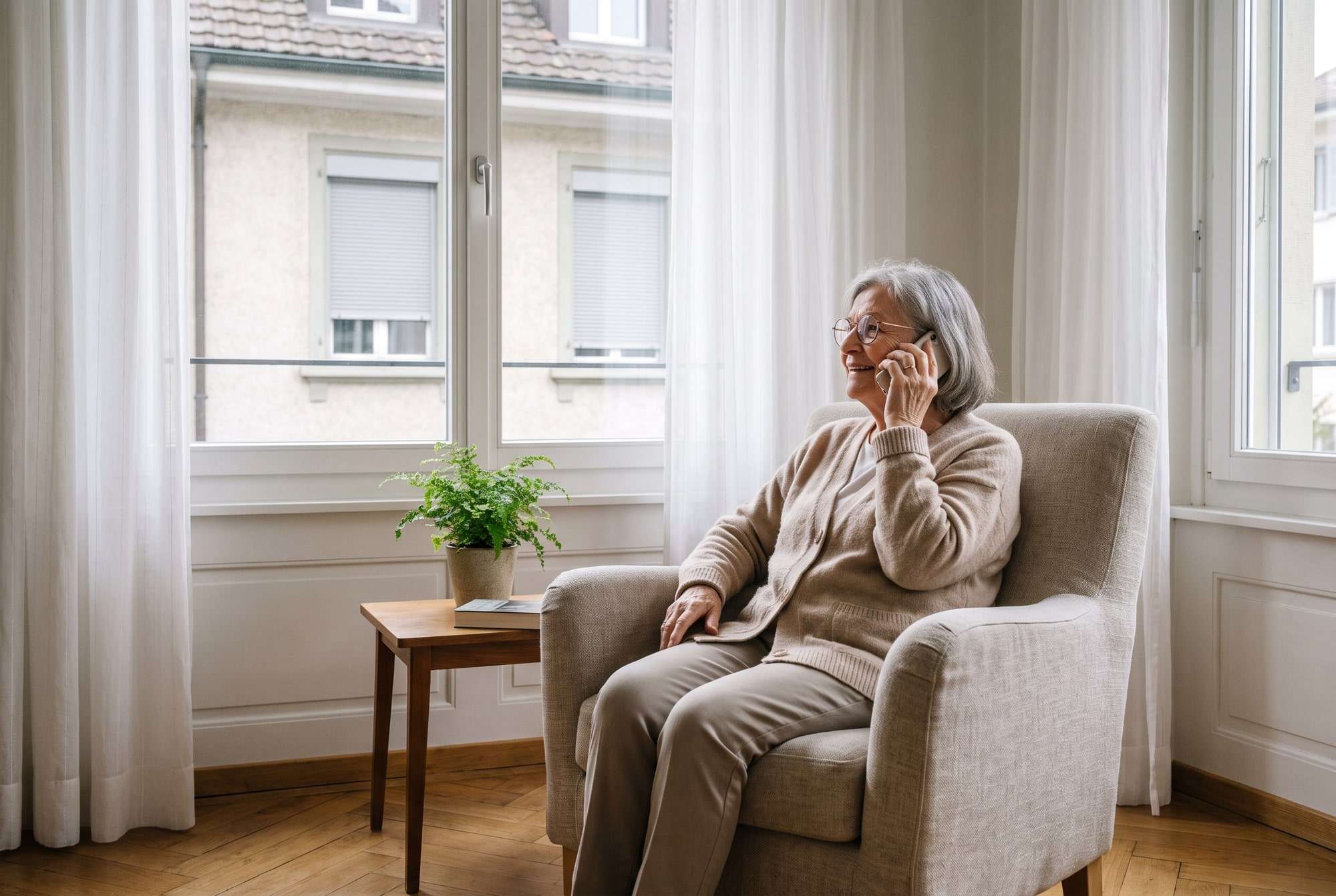 Femme âgée souriante au téléphone chez elle
